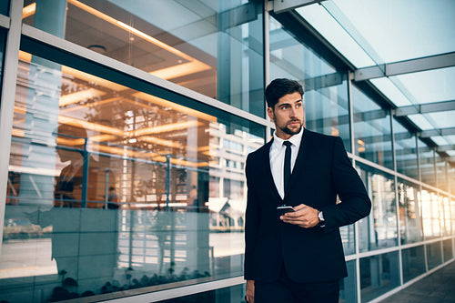 Handsome businessman walking with mobile phone