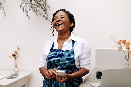 Successful small business owner using a smartphone to run her store