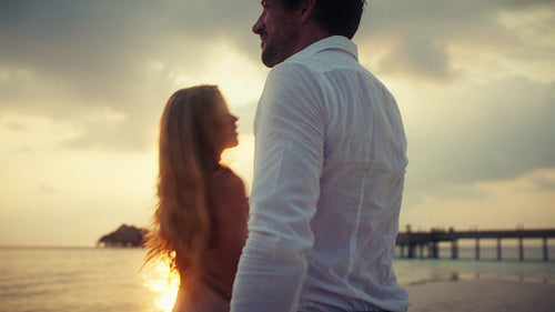 Romantic couple enjoying a beautiful beach sunset, sharing tender moments on their tropical vacation