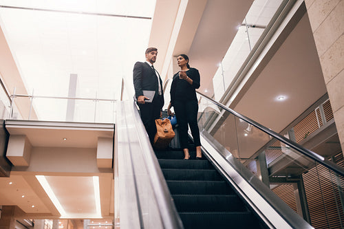 Business traveler with baggage on the escalator at the airport