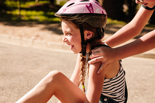 Happy girl sitting on street wearing a bicycle helmet