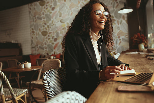 Smiling woman having a video call on her laptop at coffee shop