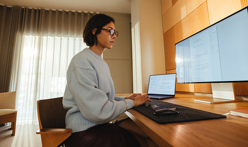 Woman concentrates on business tasks at a computer desk in a bright office