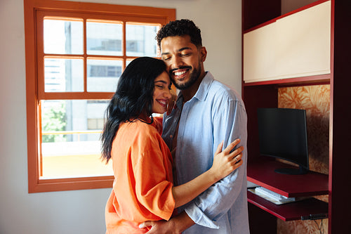 Affectionate couple embracing in their living room with natural light