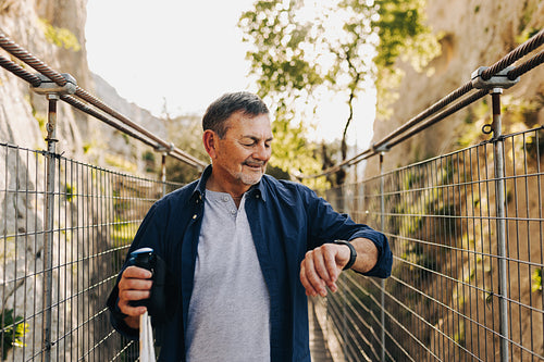 Mature man checking his watch while hiking
