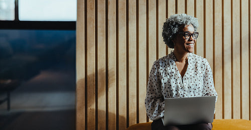Mature woman in business attire works on a laptop in a modern office