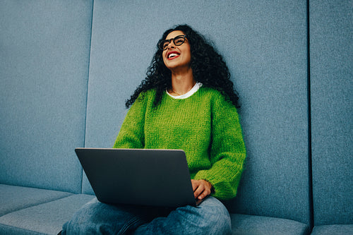 Woman smiling with laptop in study lounge