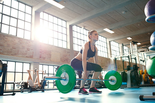 Female athlete lifting weights in health club.