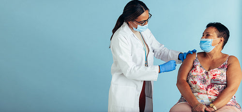 Doctor giving vaccine to senior woman