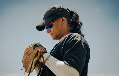 Focused female baseball player wearing sunglasses and baseball glove
