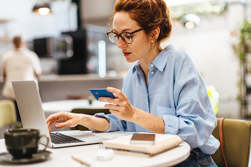 Woman using a credit card for online banking in coffee shop