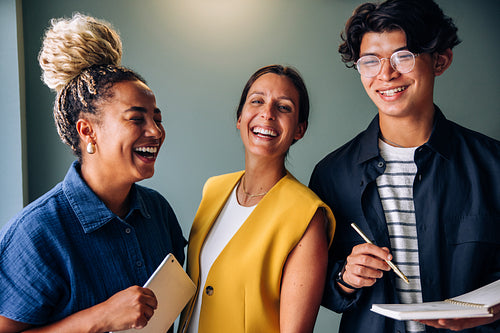 Three young businesspeople laughing together while discussing ideas