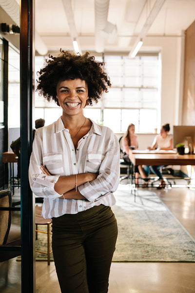 Smiling young woman leaning to office doorway
