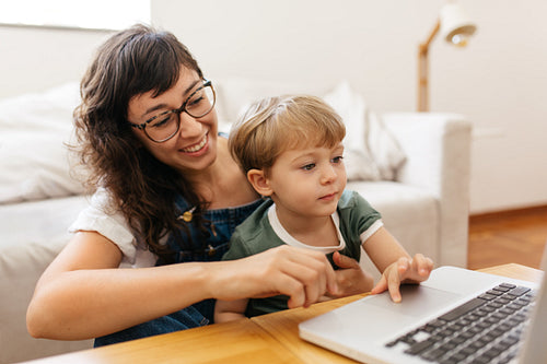 Smiling mother and son with laptop at home