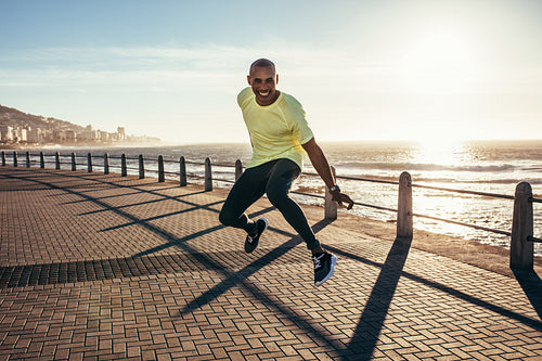 African man jumping on a road by the sea