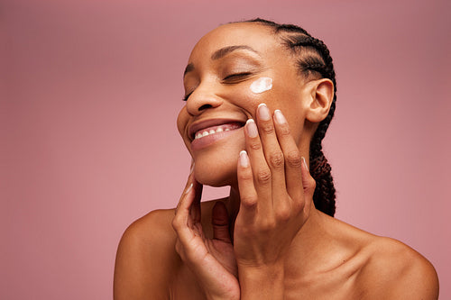 Woman applying beauty product on face