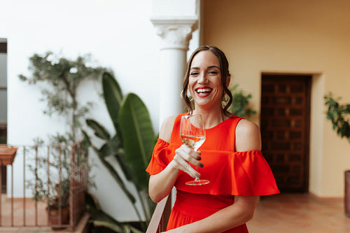 Carefree young woman toasting with a wineglass on a balcony