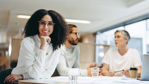 Happy young businesswoman sitting in a meeting with her team