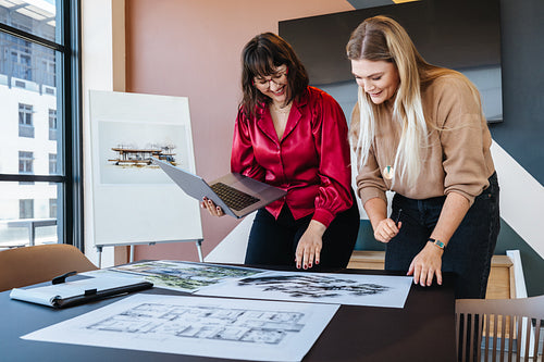 Two women reviewing architectural blueprints at a collaborative workspace