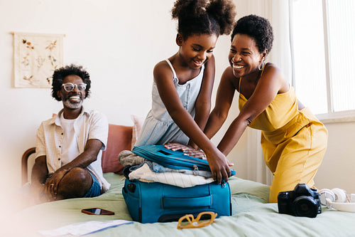 Excited mom and daughter packing a suitcase for fun family holiday