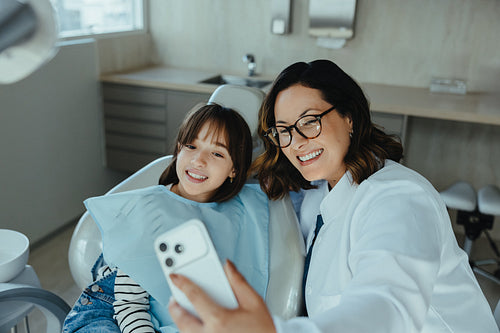 Together, the dentist and child patient smile for a selfie in the clinic