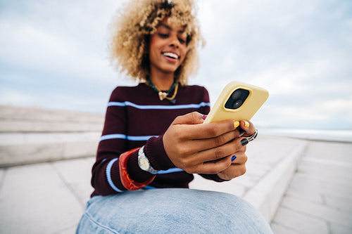 Young woman smiling while using phone outdoors