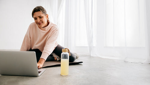 Yoga and fitness come together as a woman uses a laptop for class at home