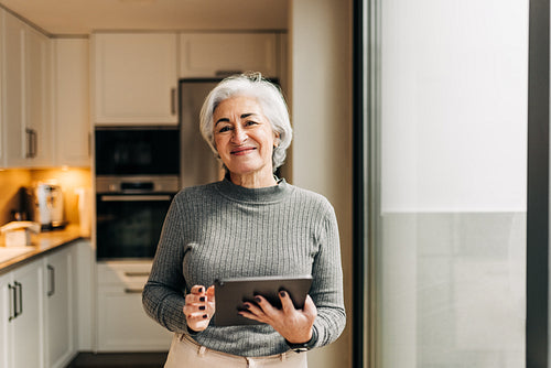 Happy senior woman holding a digital tablet at home