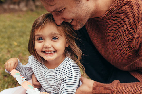 Little girl with her father outdoors holding a candy 
