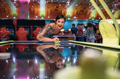 Woman having fun playing air hockey game at a gaming parlour
