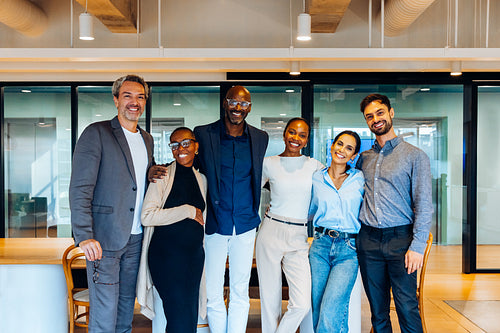 Group of cheerful professionals posing confidently in a contemporary office environment