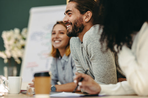 Happy young businessman attending a meeting with his team