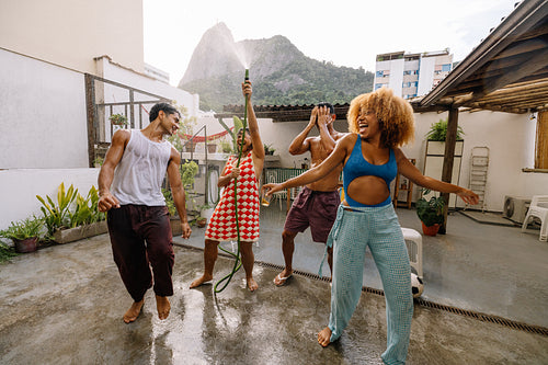 Laughing friends raise the hose high in a playful banho de mangueira in Rio