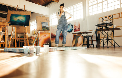 Thoughtful female painter looking at her painting
