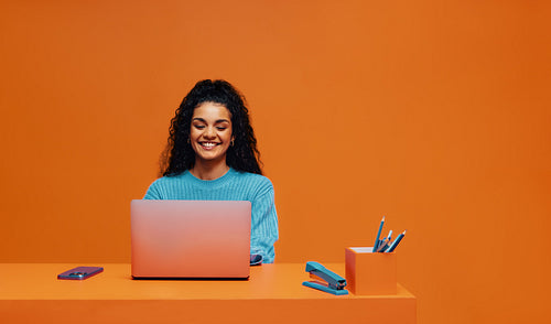 Happy woman using laptop while working in colorful office