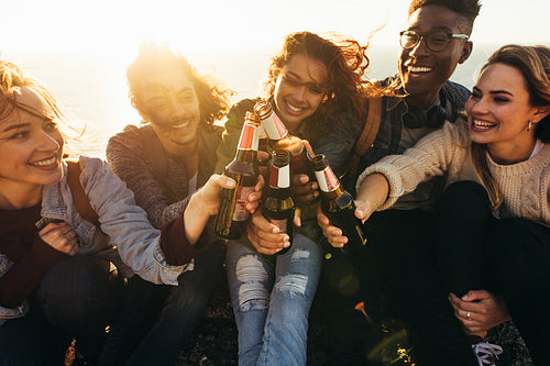 Multi-ethnic group of people toasting beers outdoors