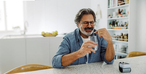 Senior man takes medication for blood pressure at home