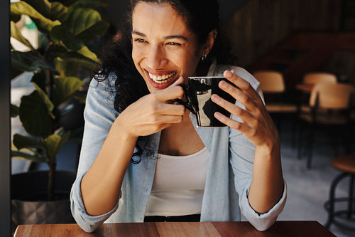 Smiling woman enjoying coffee at cafe