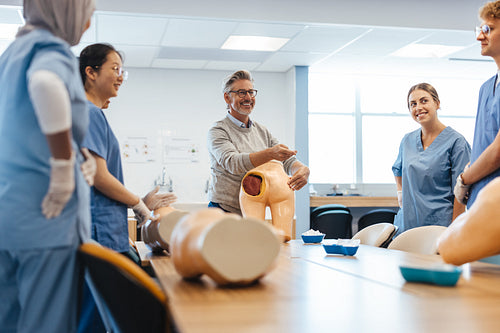 Experienced medical practitioner giving injection training to young students in medical school