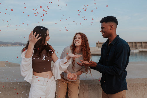 Diverse friends celebrating with red and white confetti outdoors