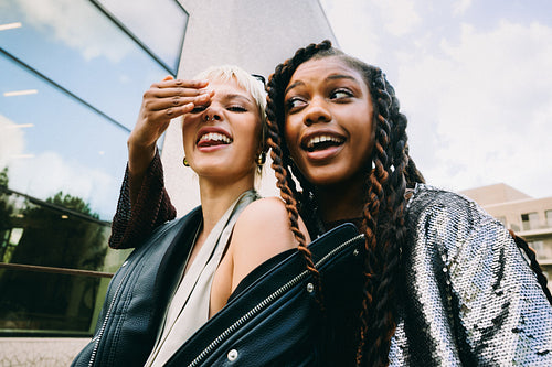 Best friends pose together outside a city building