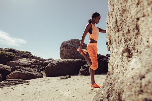African woman stretching her legs at beach