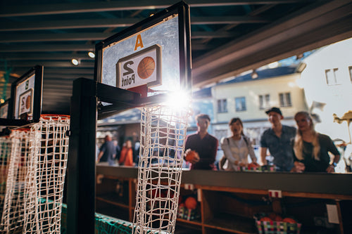 Young people playing basketball game at amusement park