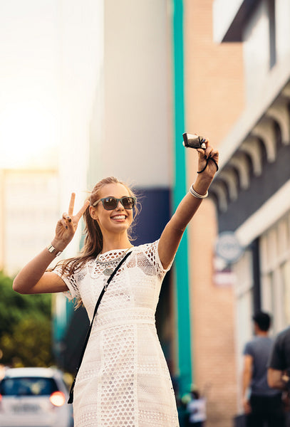 Tourist taking selfie in a street using a digital camera.
