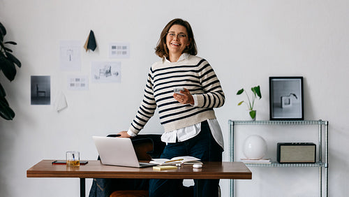 The woman takes a break at her creative office desk with a laptop nearby