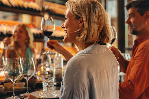 Group of adults toasting with glasses of red wine at a wine bar