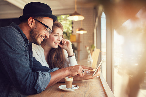 Couple using a digital tablet at coffee shop
