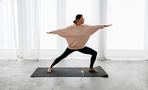 In a home workout scene, yoga becomes a strong warrior pose for the woman