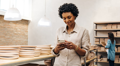 Ethnic ceramist reading a text message on her smartphone