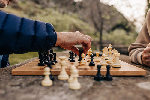 Elderly couple playing chess together outdoors
